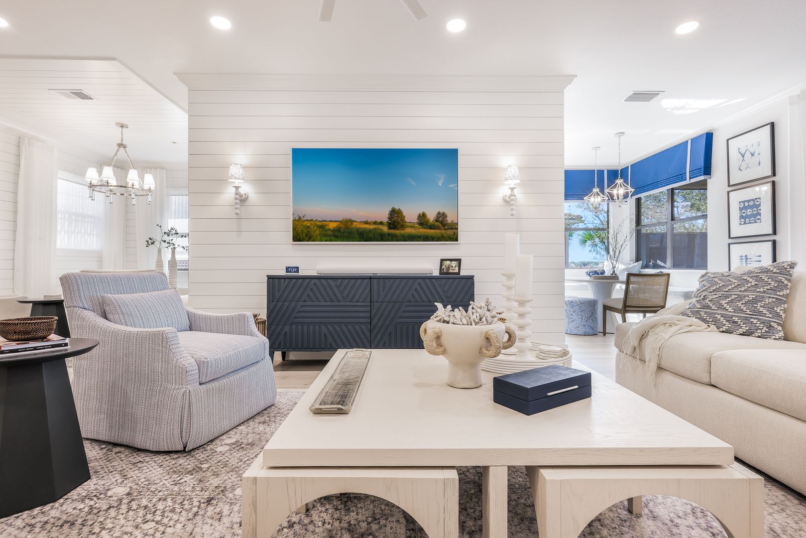 A living room with a couch , chair , coffee table and a painting on the wall.