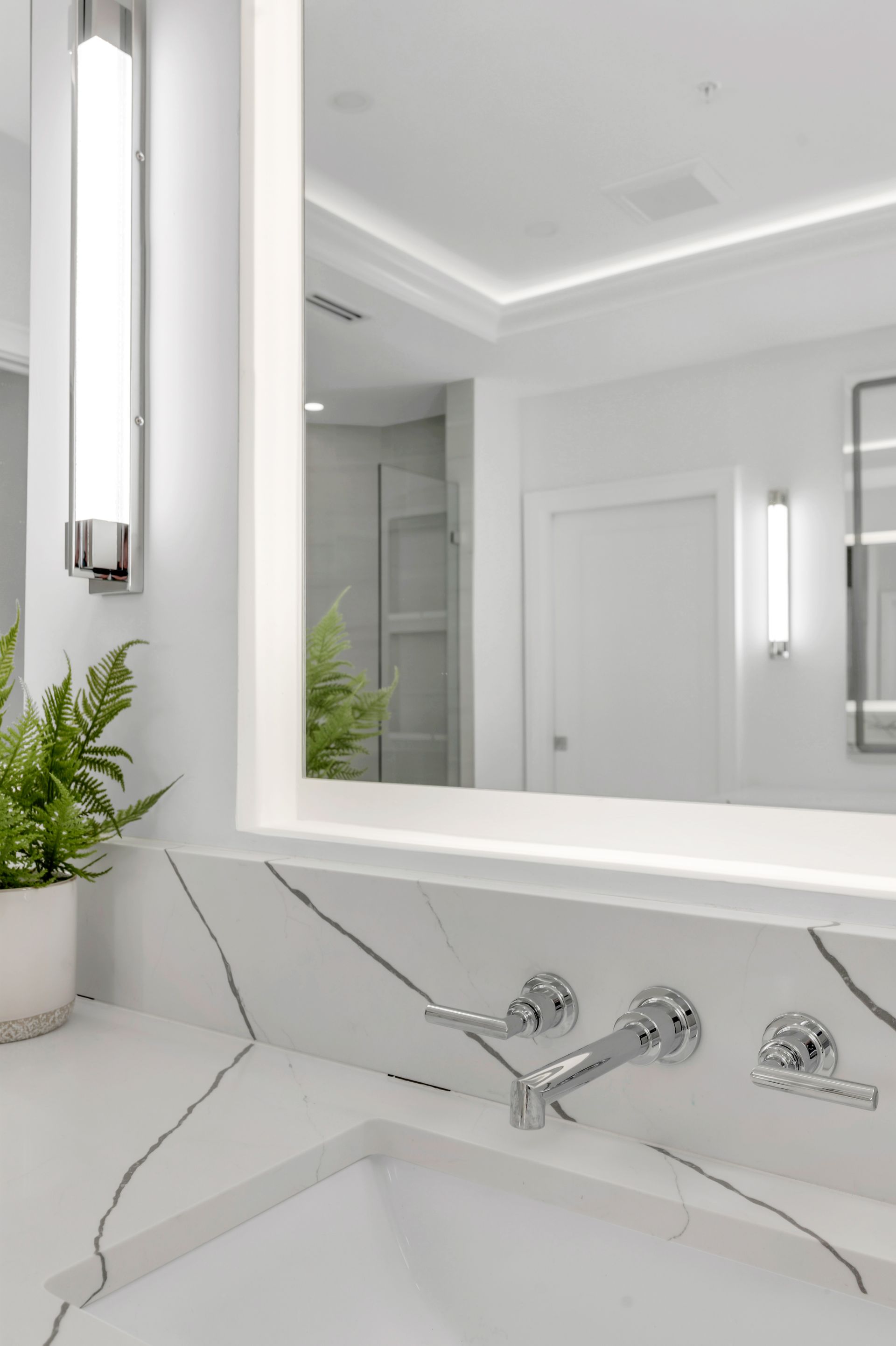 A bathroom with a sink , mirror and light.