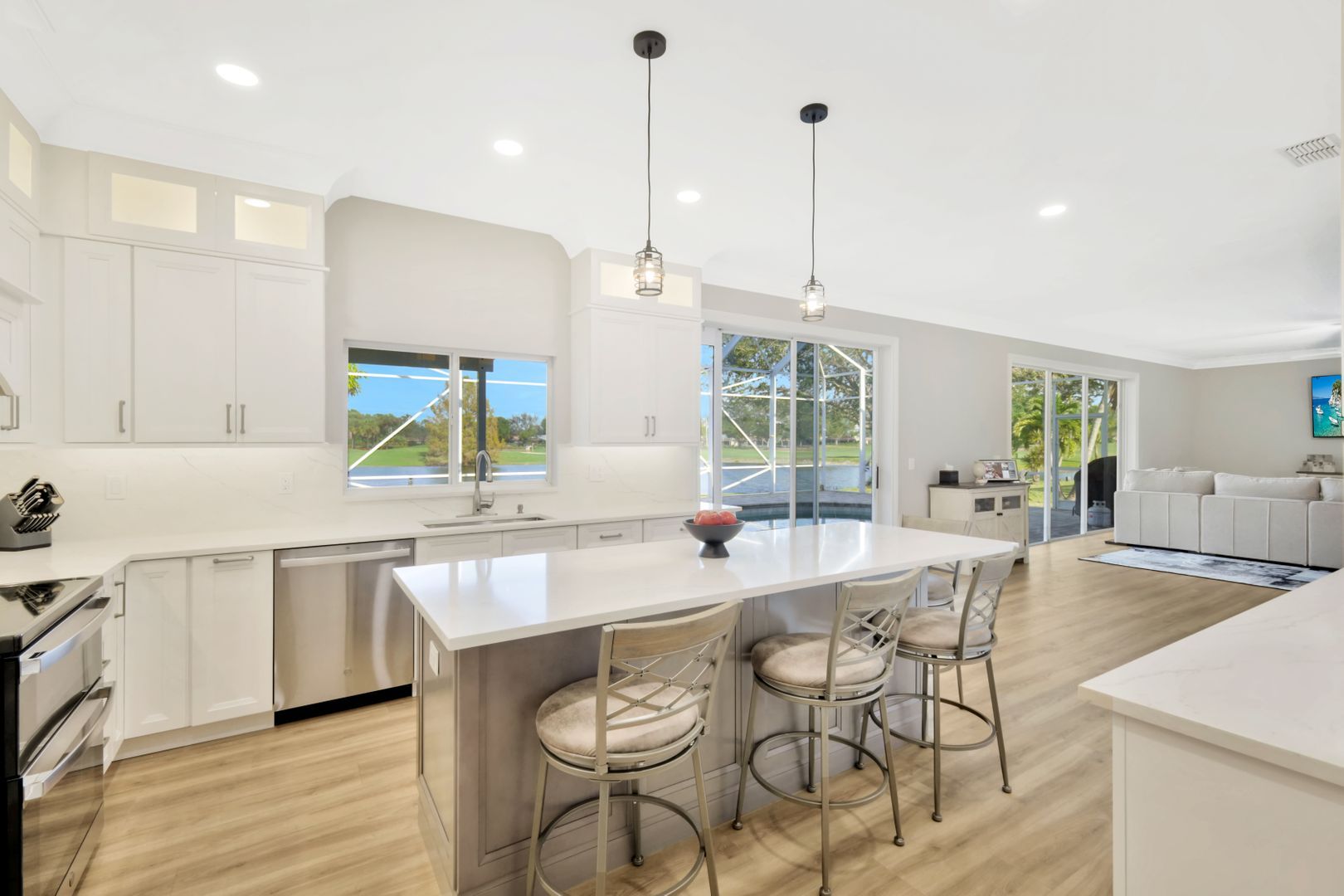 A kitchen with white cabinets and stainless steel appliances and a large island.