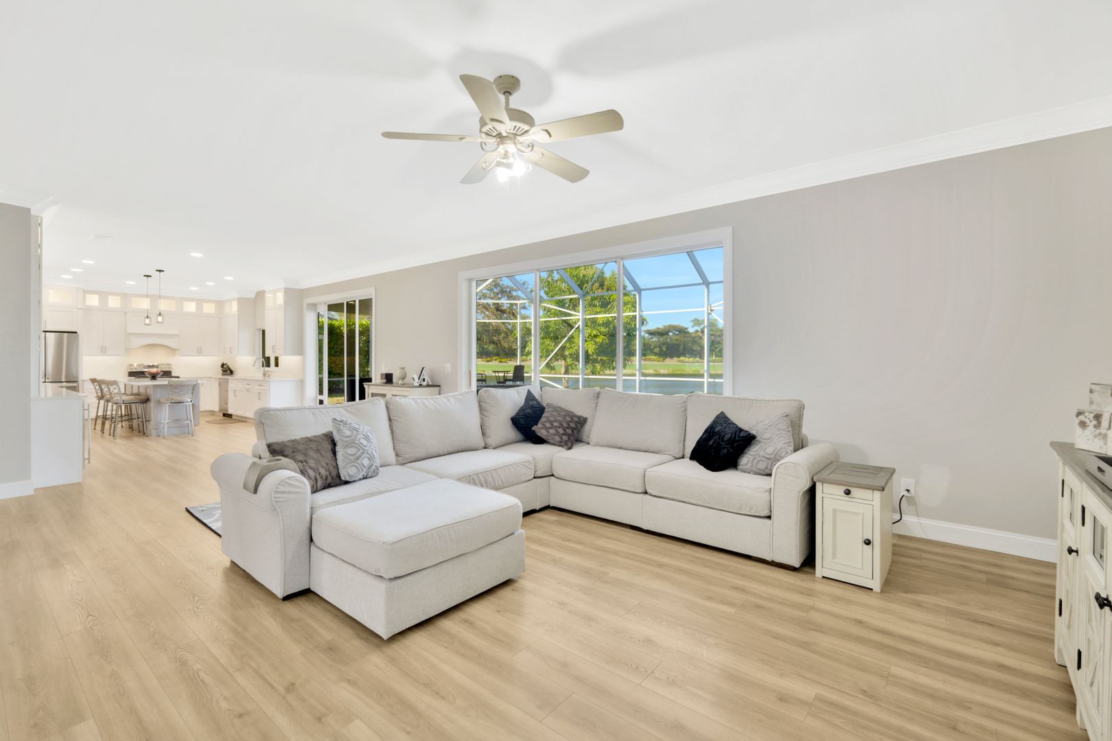 a living room with a large sectional couch and a ceiling fan .