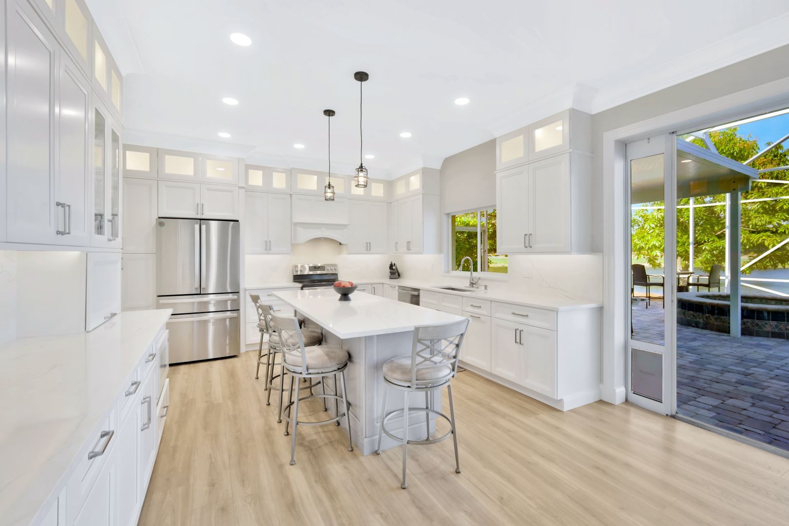 A kitchen with white cabinets , stainless steel appliances , and a large island.