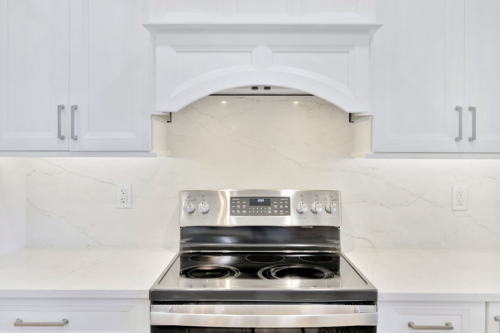 A stainless steel stove top oven in a kitchen with white cabinets.
