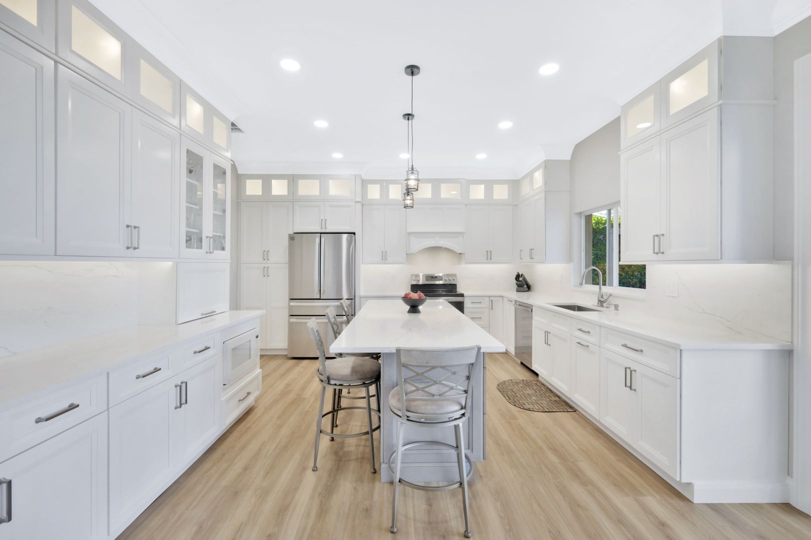 a kitchen with white cabinets , stainless steel appliances , and a large island .