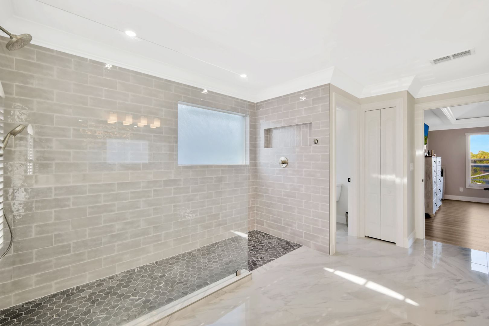 A bathroom with a walk in shower and a window.