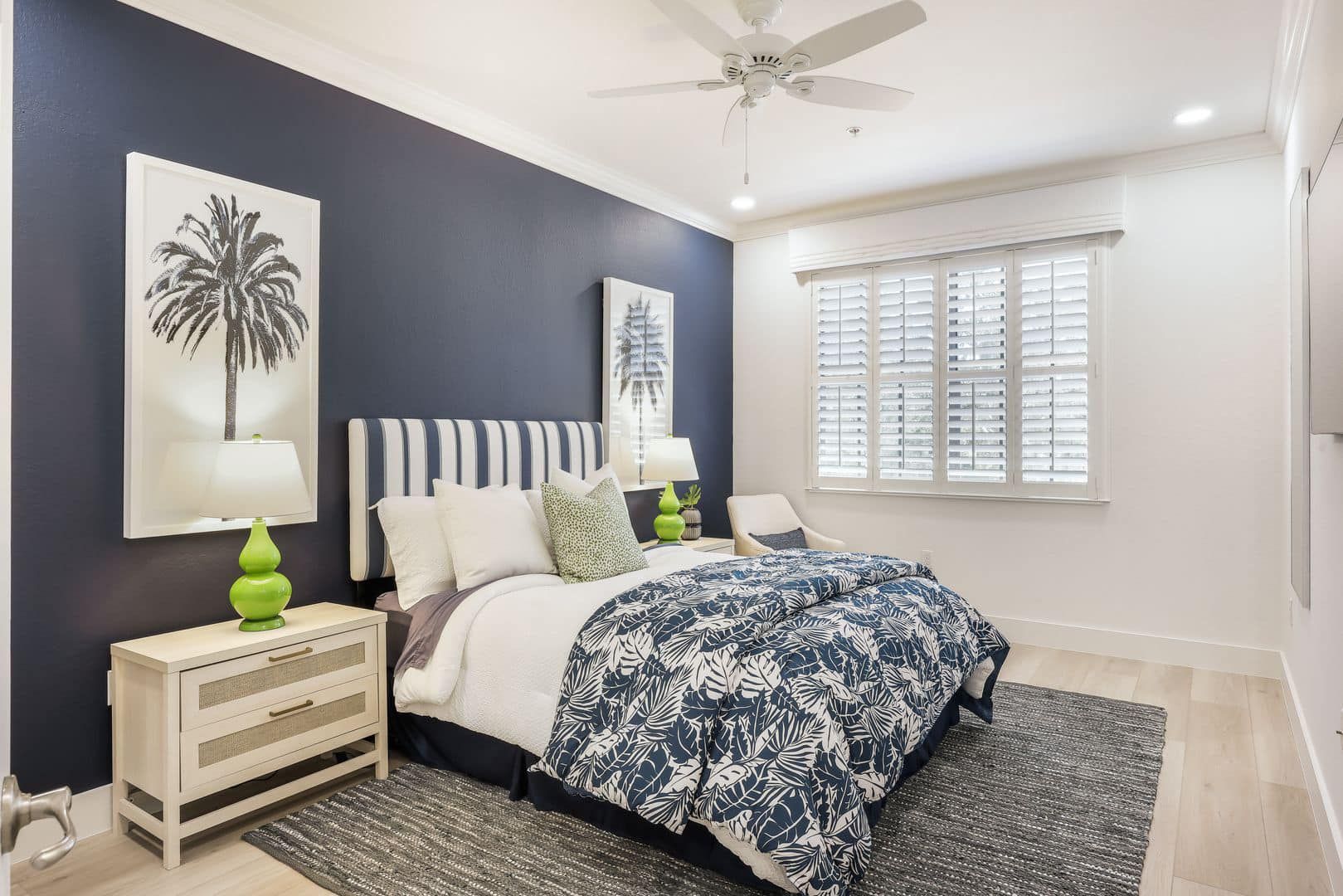 A bedroom with a bed , nightstand , lamps and a ceiling fan.