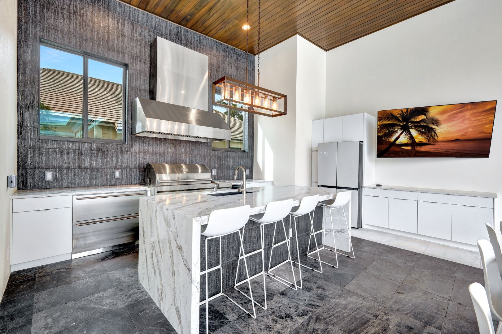 A kitchen with a large island and a painting of a palm tree on the wall.