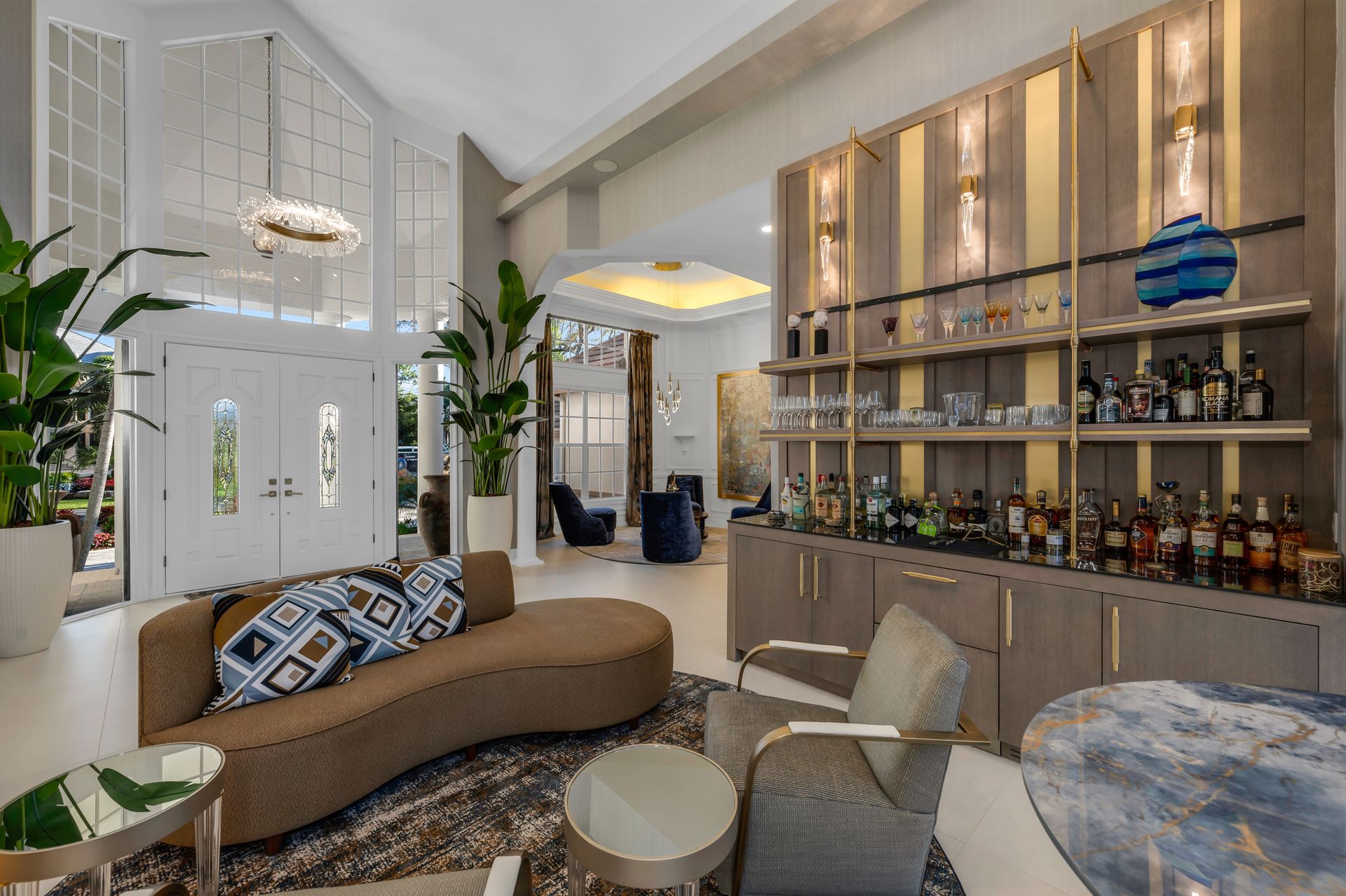 A living room with a couch , chairs , tables and a bar.