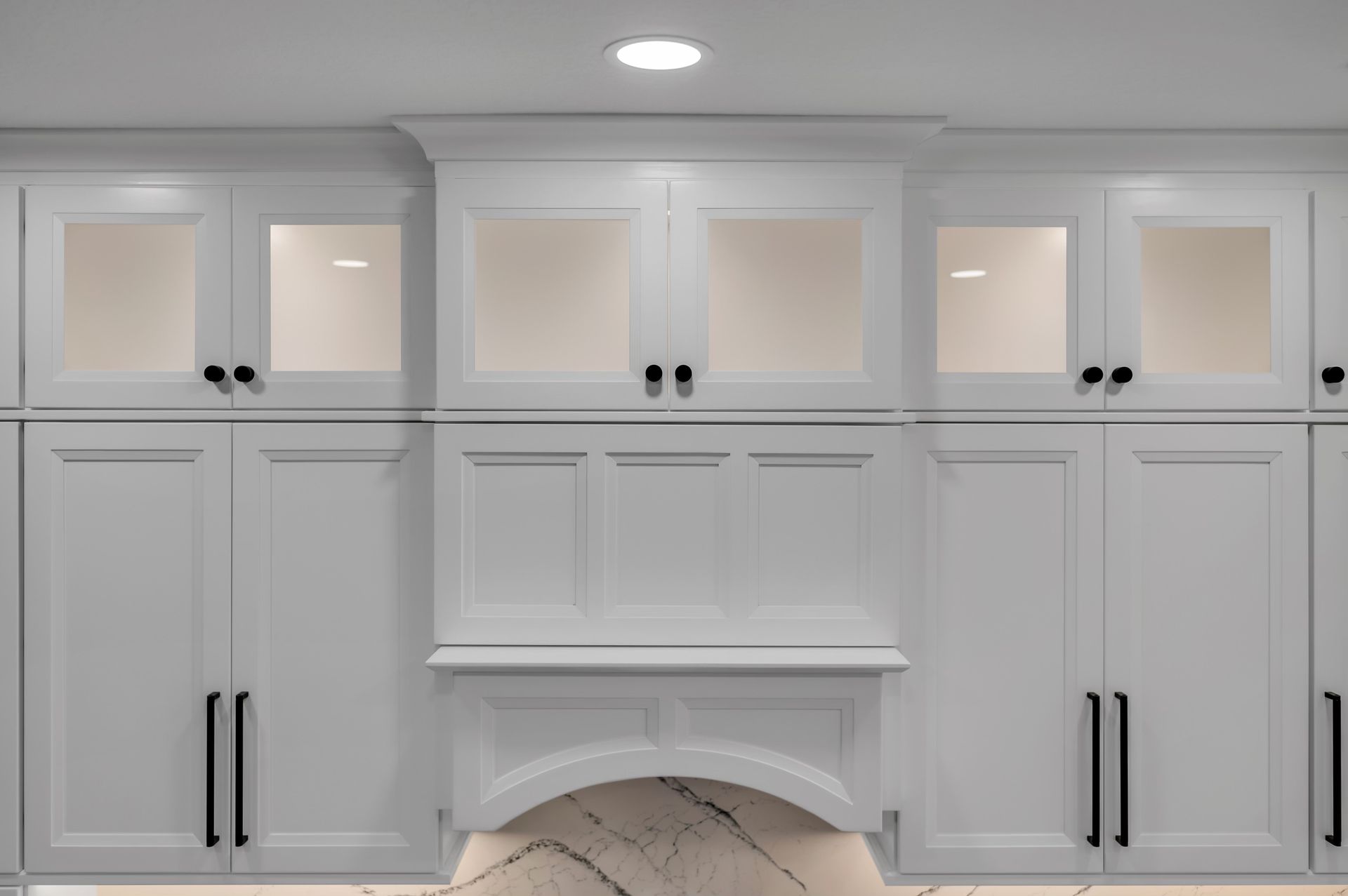 A kitchen with white cabinets and black handles and a fireplace.