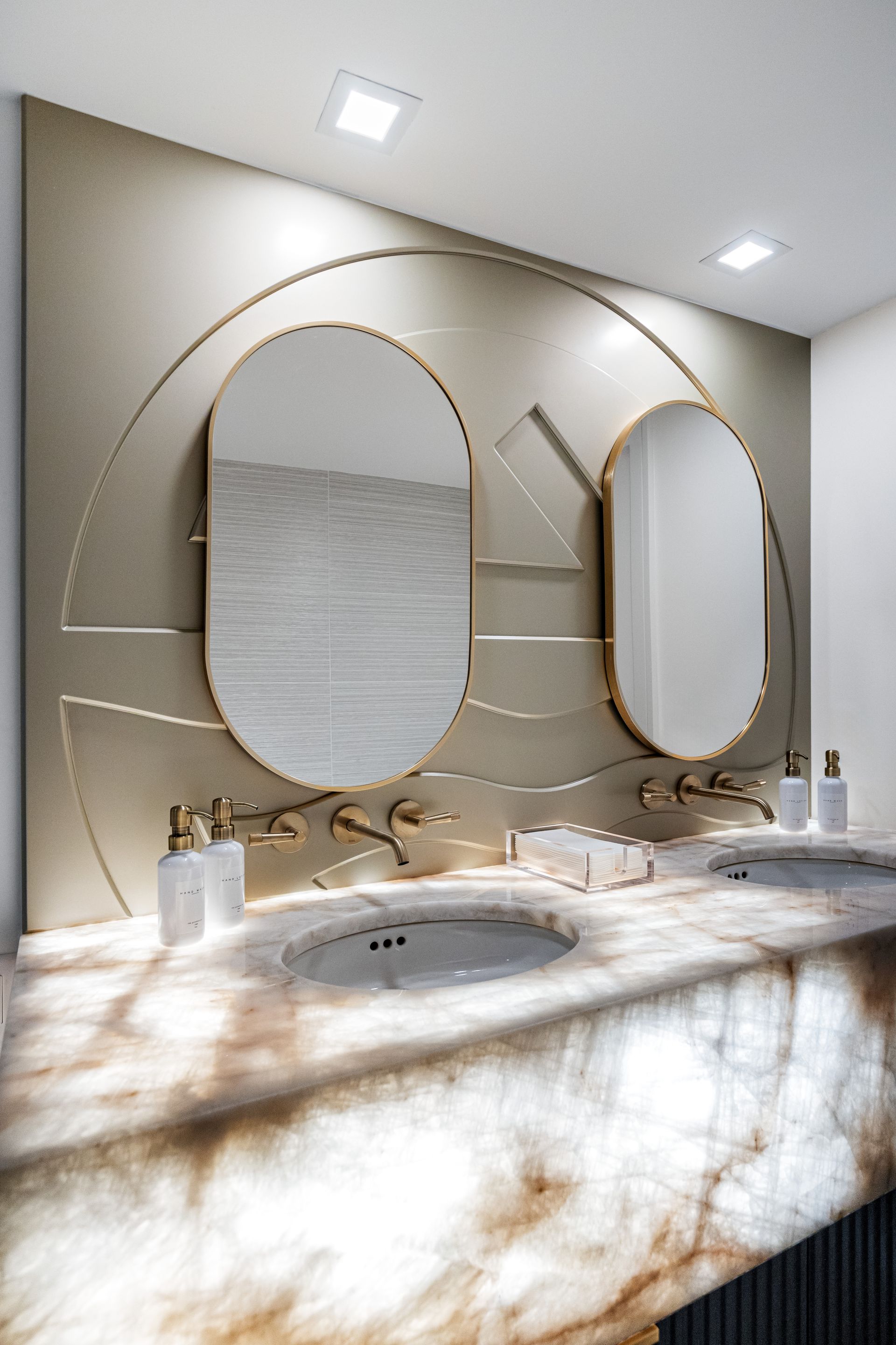 a bathroom with two sinks , two mirrors , and white cabinets .