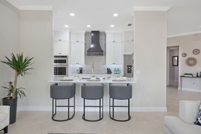 A kitchen with a bar and three stools in a living room.