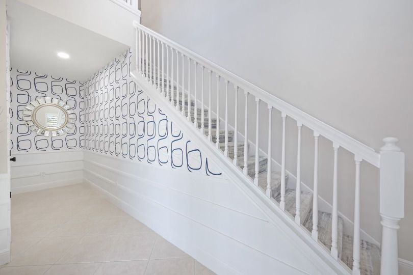 A staircase with a white railing and a wall with the alphabet on it