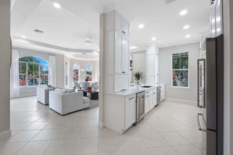 A kitchen with white cabinets and stainless steel appliances is connected to a living room and dining room.