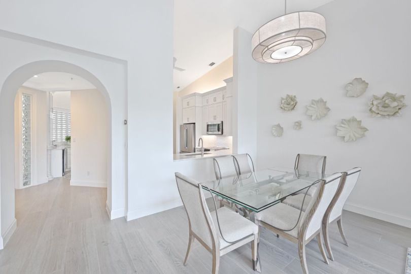 A dining room with a glass table and white chairs