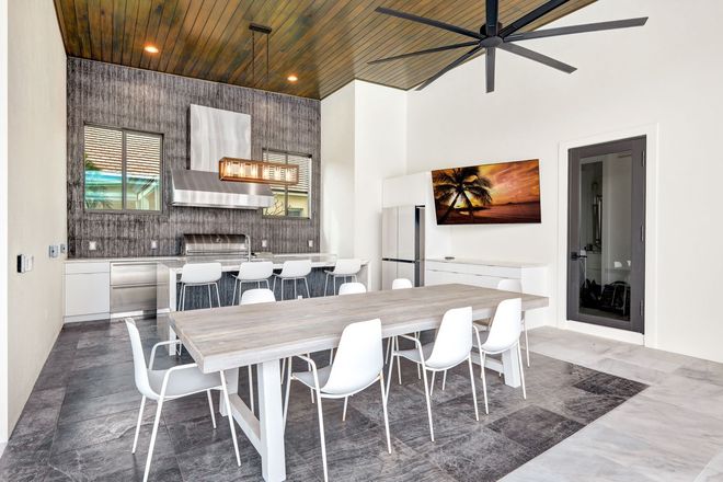 A dining room with a large table and chairs and a ceiling fan.