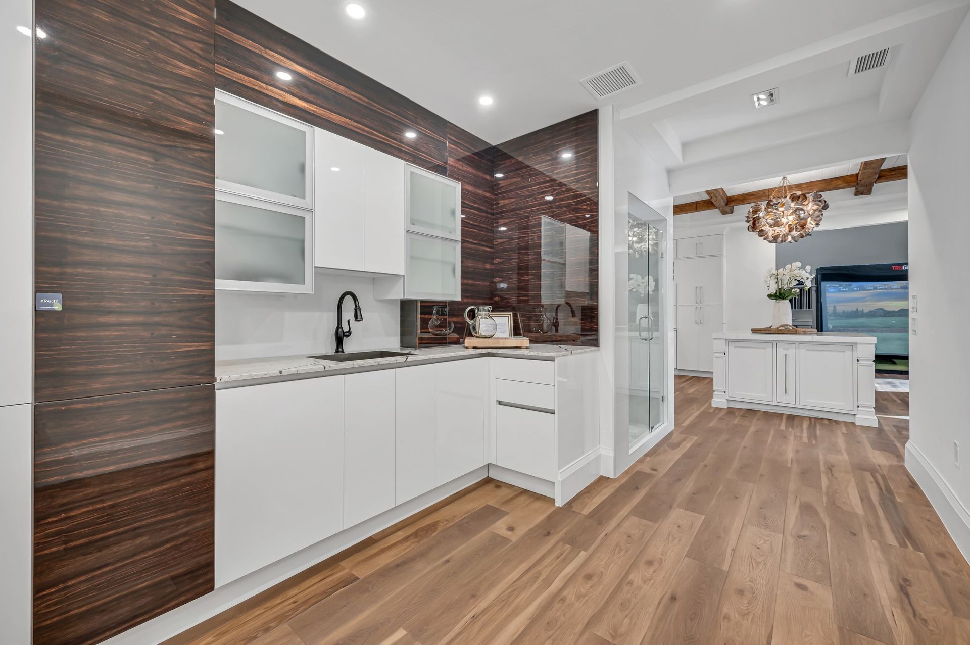 A kitchen with white cabinets and wooden floors.