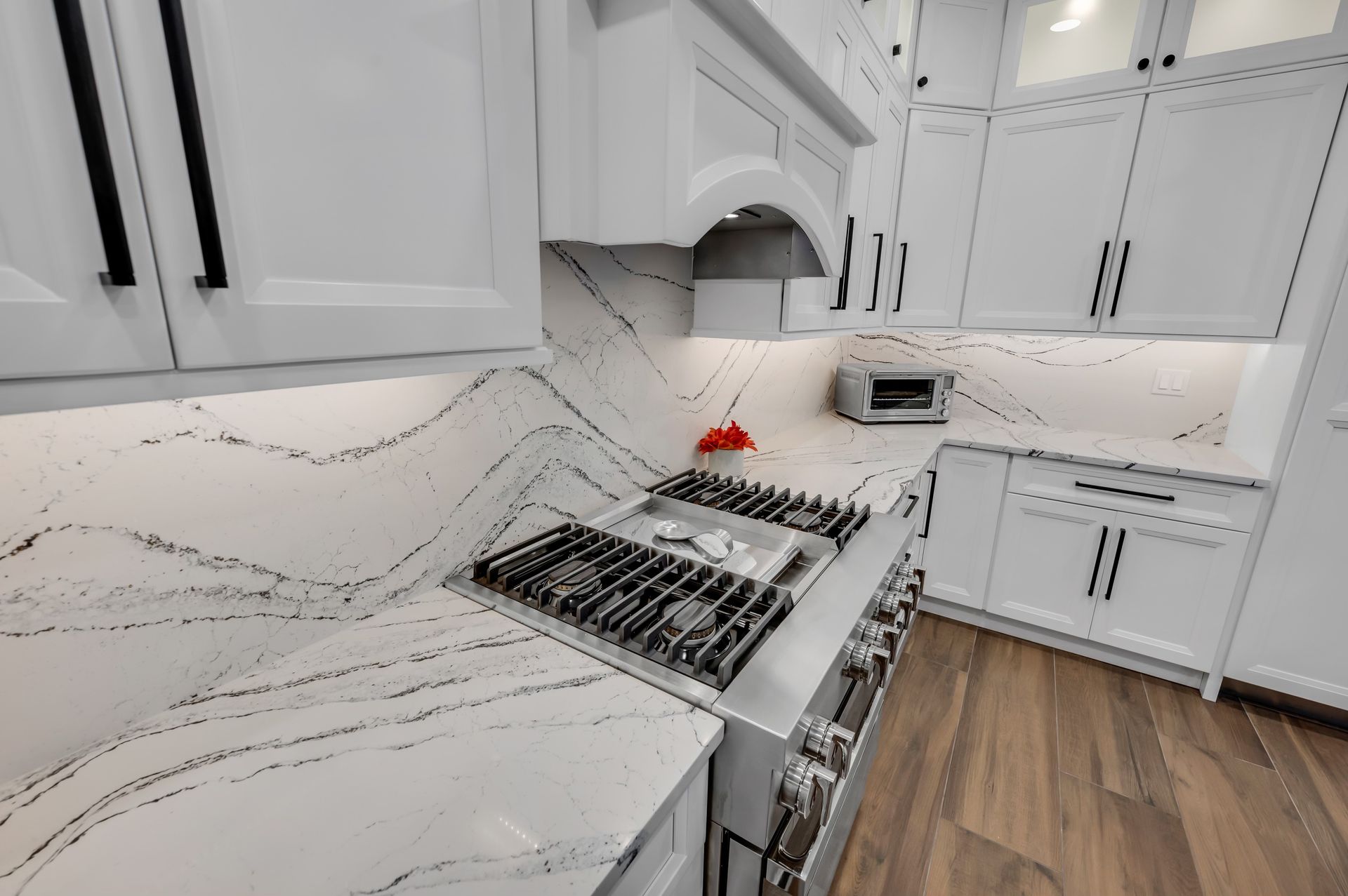 A kitchen with white cabinets and a stove top oven