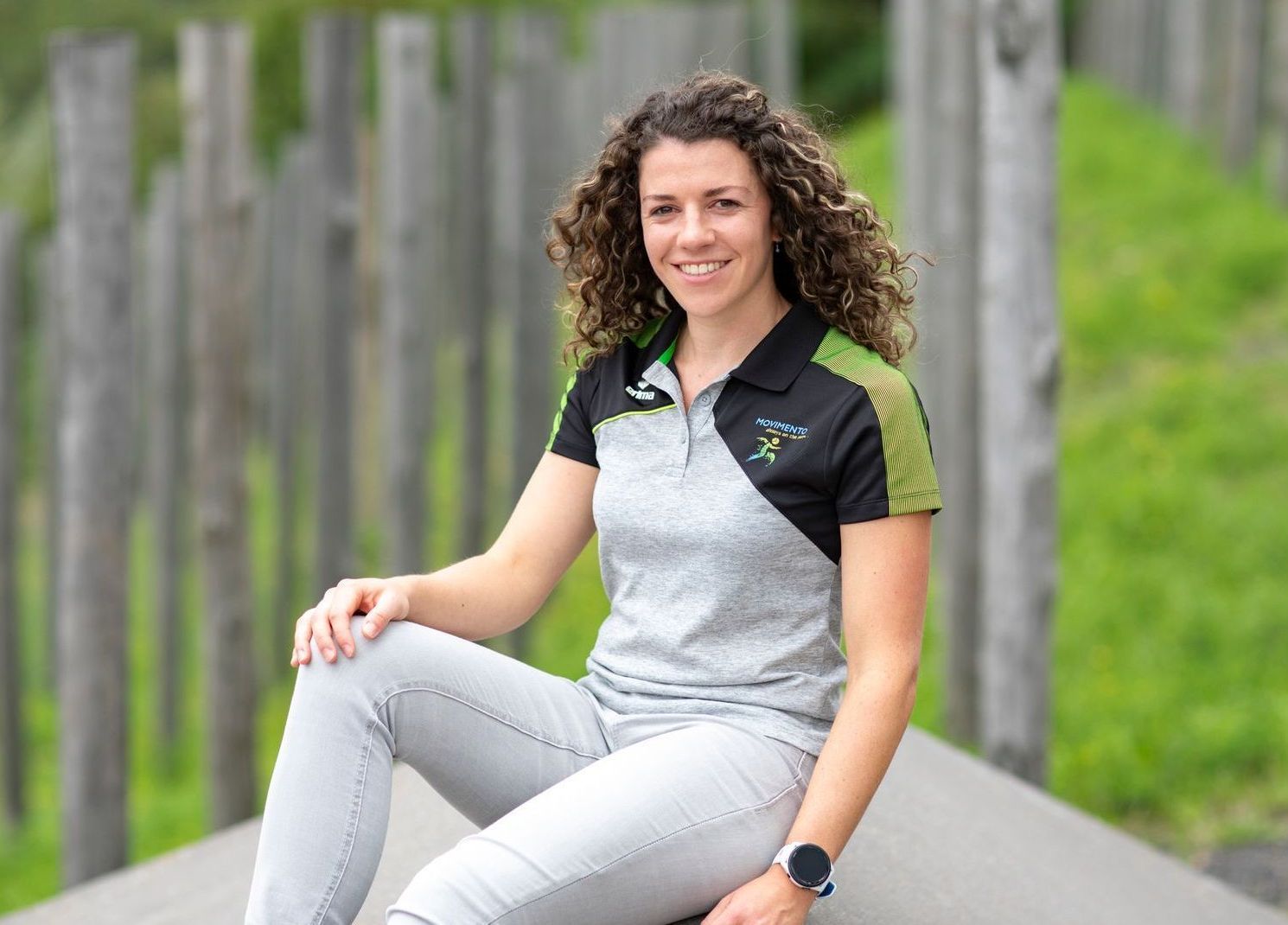 Een vrouw, gekleed in een zwart en grijs poloshirt, zit op de grond