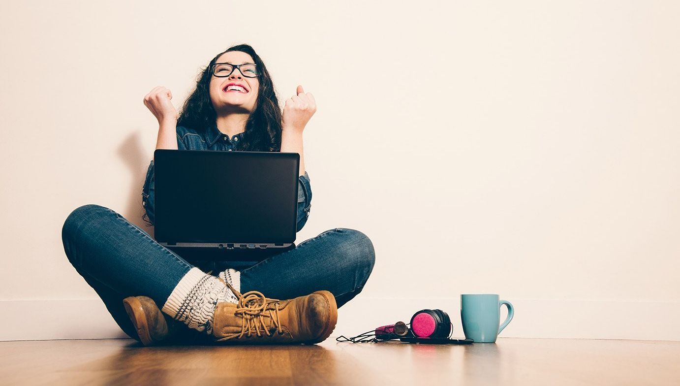 Een vrouw zit op de grond met een laptop
