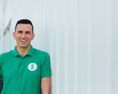 Een man die een groen shirt draagt ​​met de letter s erop