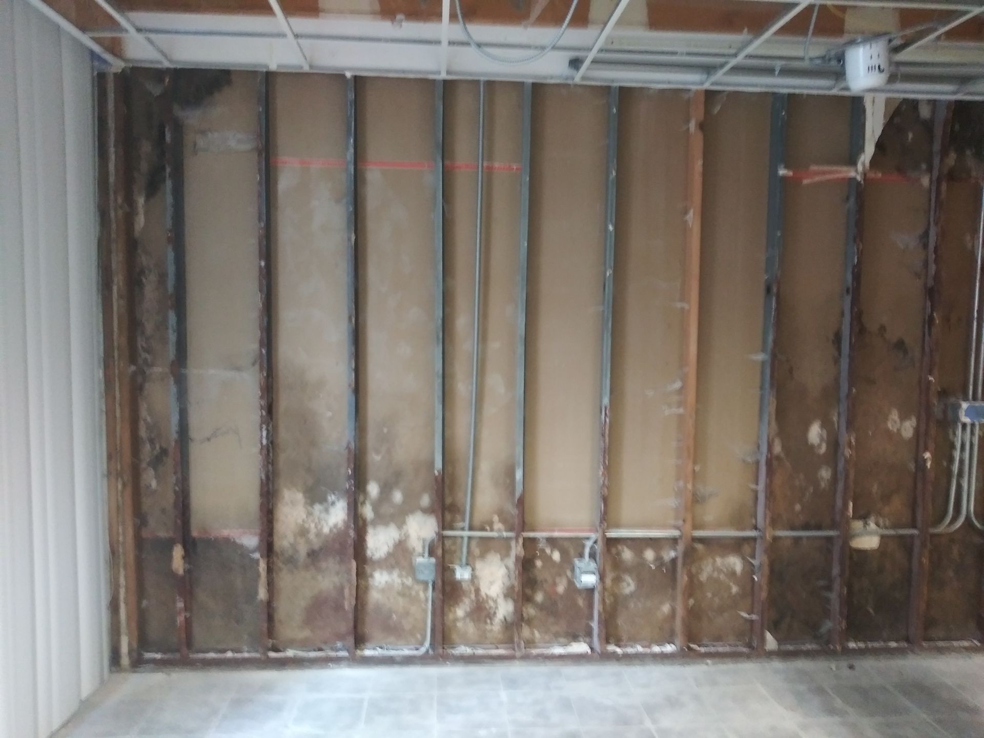 A room with a concrete floor and a wall with a lot of holes in it