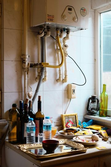 A kitchen counter with bottles of wine and a heater on the wall.