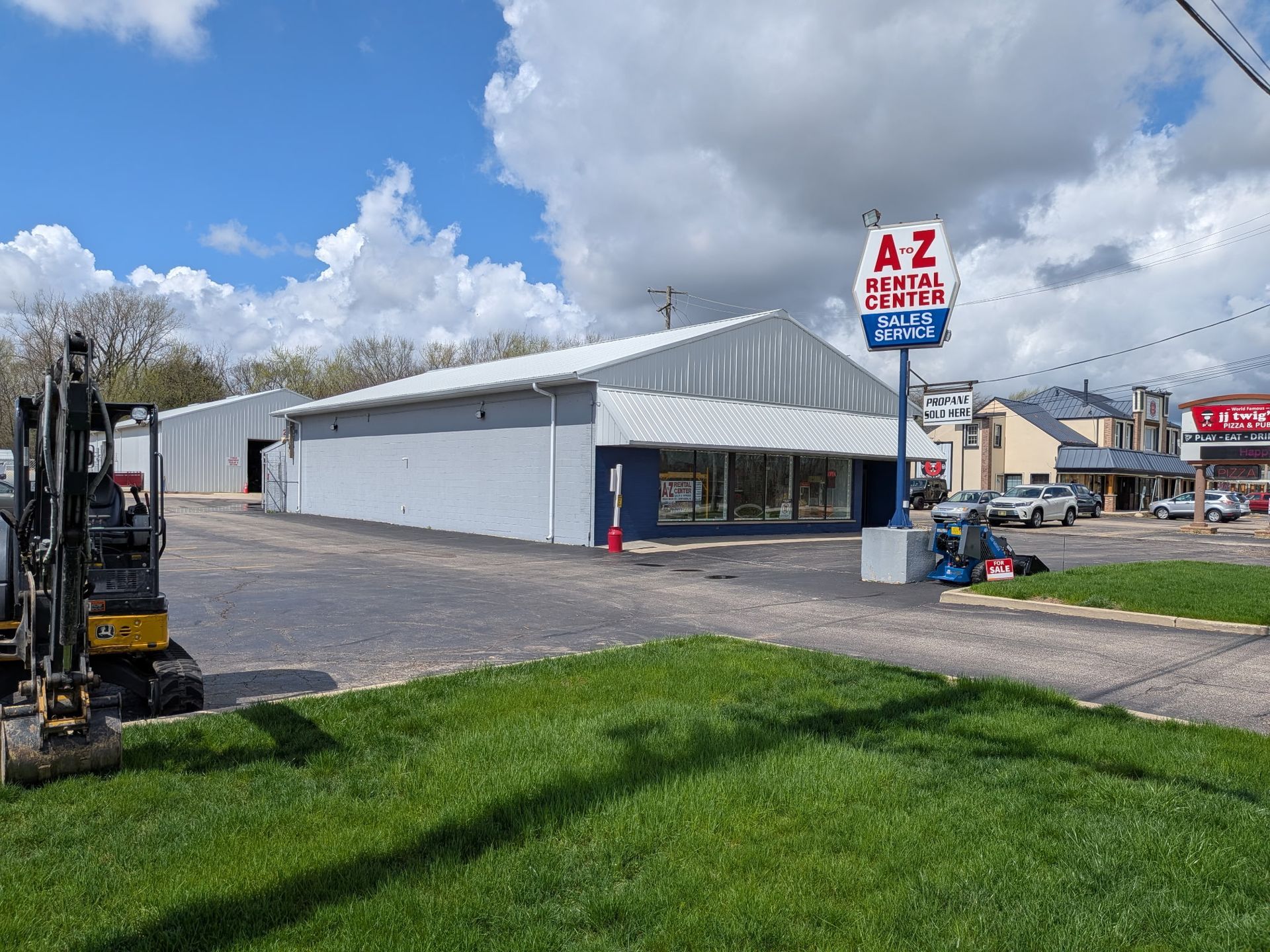 A&Z Rental Sales lot with white building, parked forklift, grassy foreground, and cloudy sky