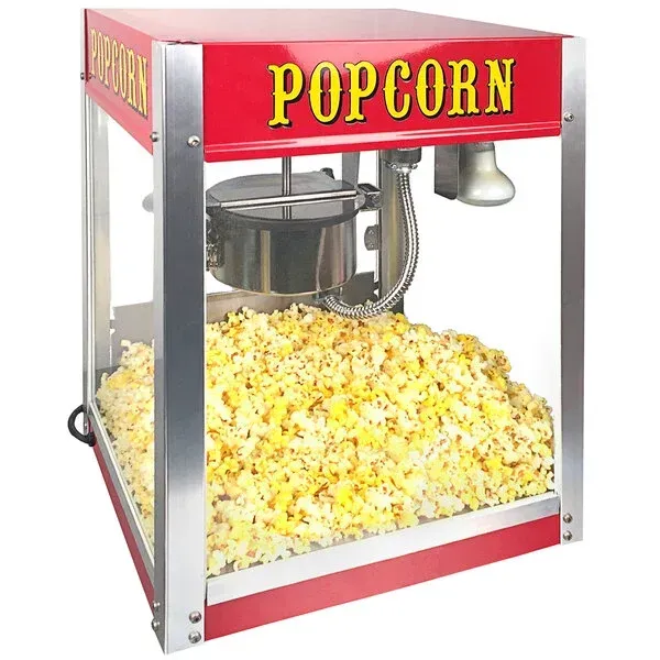 Red popcorn machine with glass sides, filled with popcorn and a red “POPCORN” sign