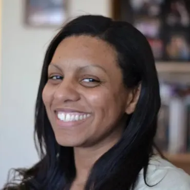A woman with long black hair is smiling for the camera