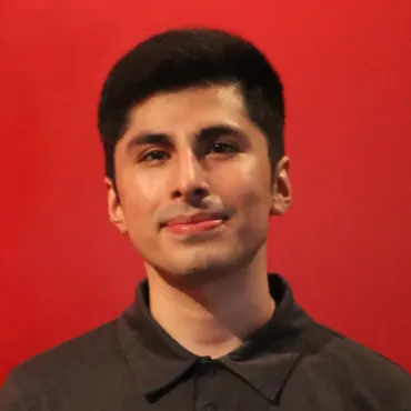 A man in a black shirt is smiling in front of a red background