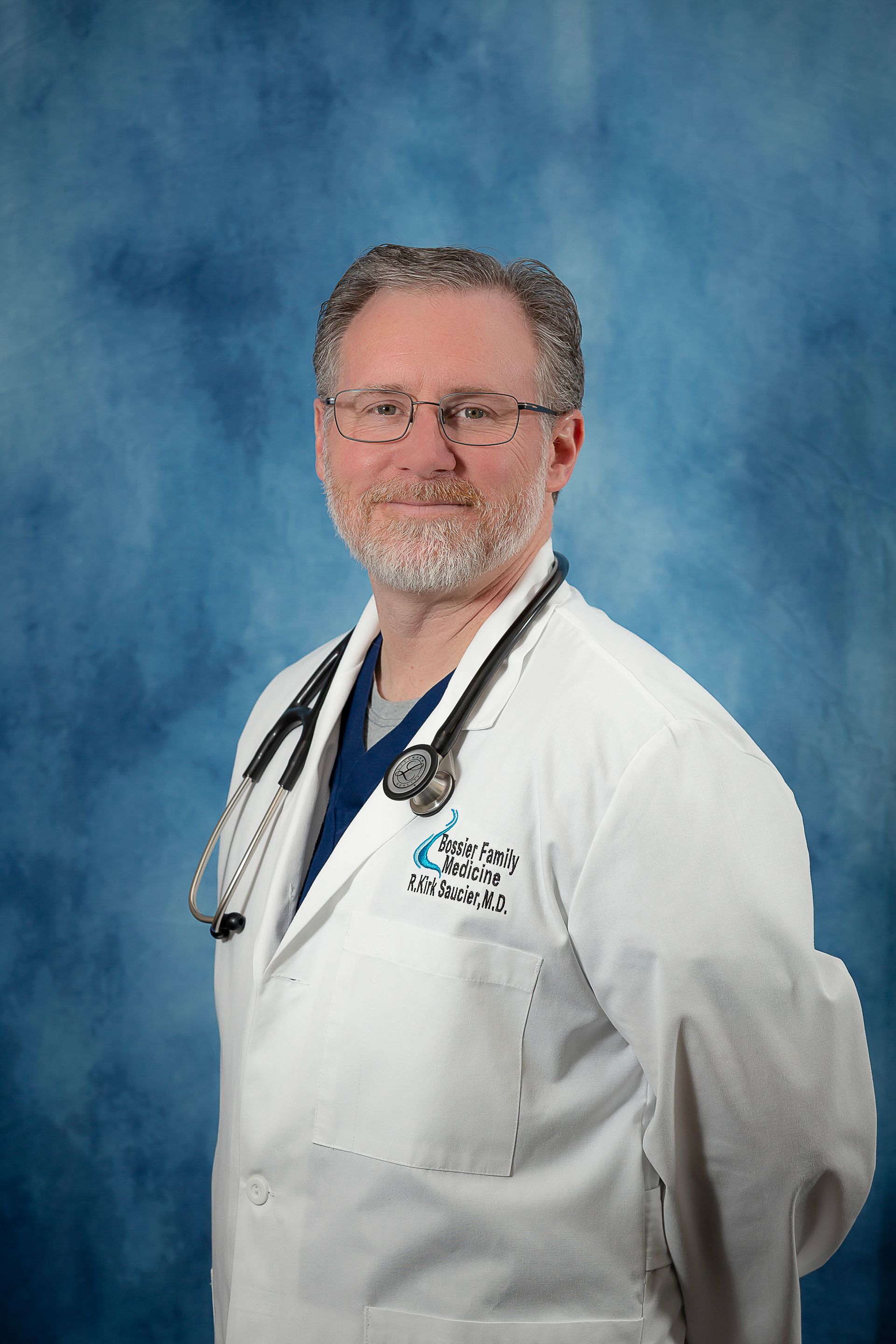 A man in a white lab coat with a stethoscope around his neck is standing in front of a blue background.