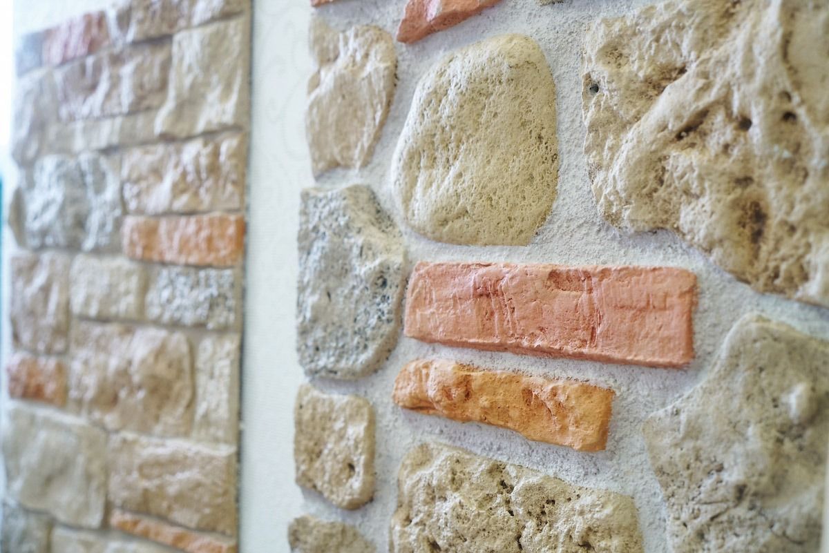 Primo piano di un muro di pietra con pietre beige e dettagli in mattoni arancioni.
