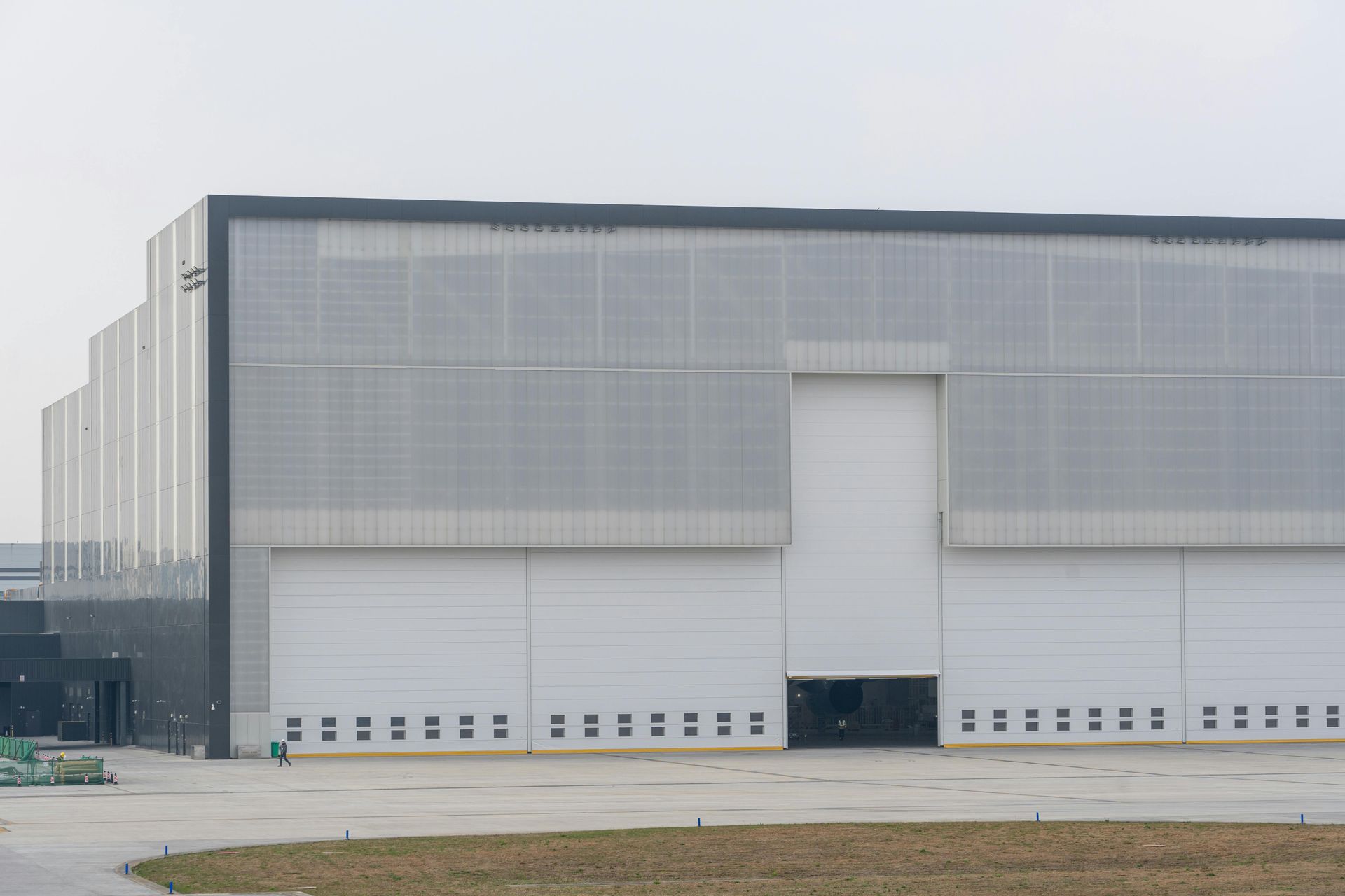 Large industrial warehouse with gray walls and tall loading doors on an overcast day