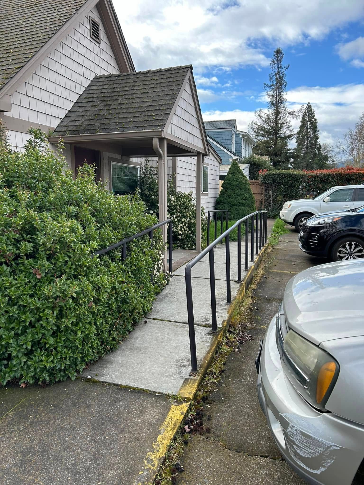A car is parked next to a ramp leading to a building.