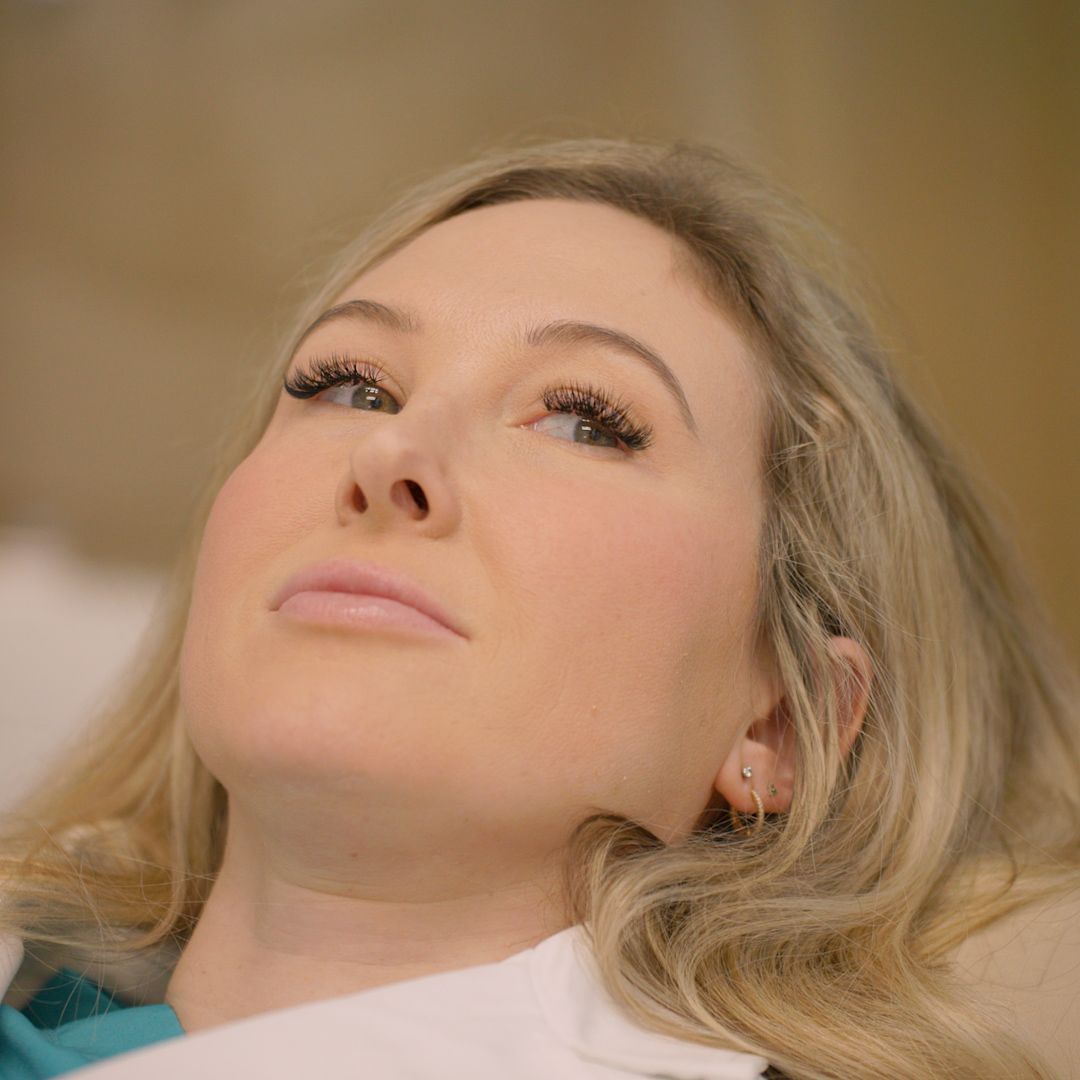 A woman is laying in a dental chair and looking up.