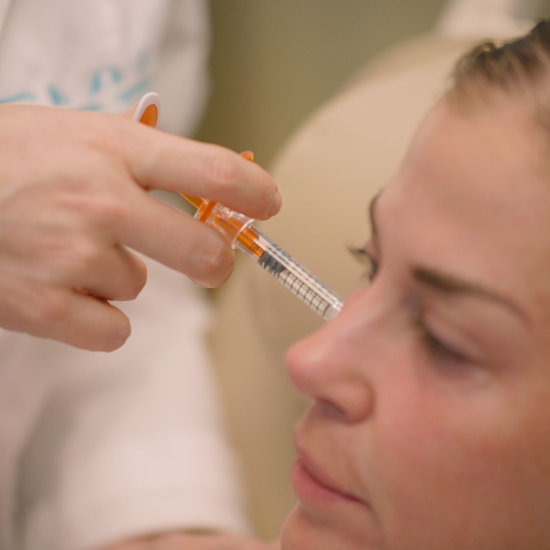 A woman is getting an injection in her face by a doctor