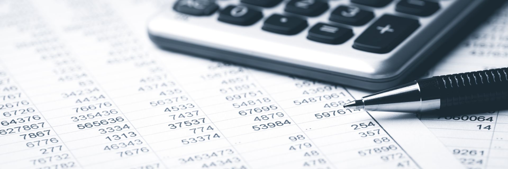 Close view of a pen and a calculator on top of papers with numbers, representing accounting.