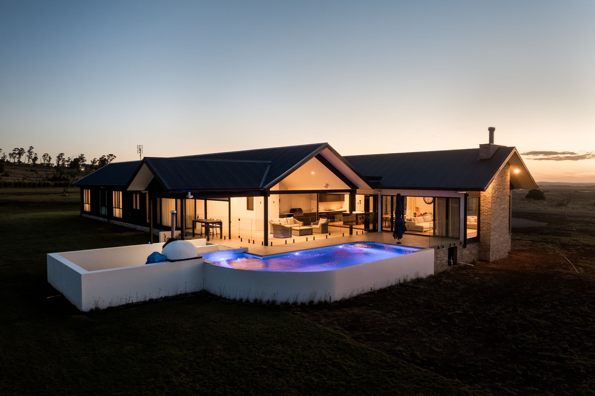 A modern house with a stone wall and a walkway leading to the front door.