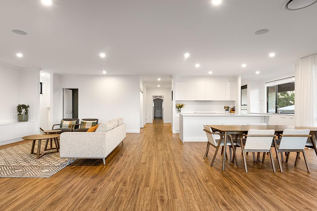 a living room and dining room in a house with wooden floors and white walls .