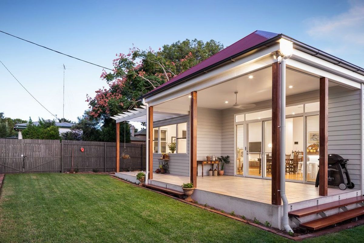 a small house with a porch and a fence in the backyard .