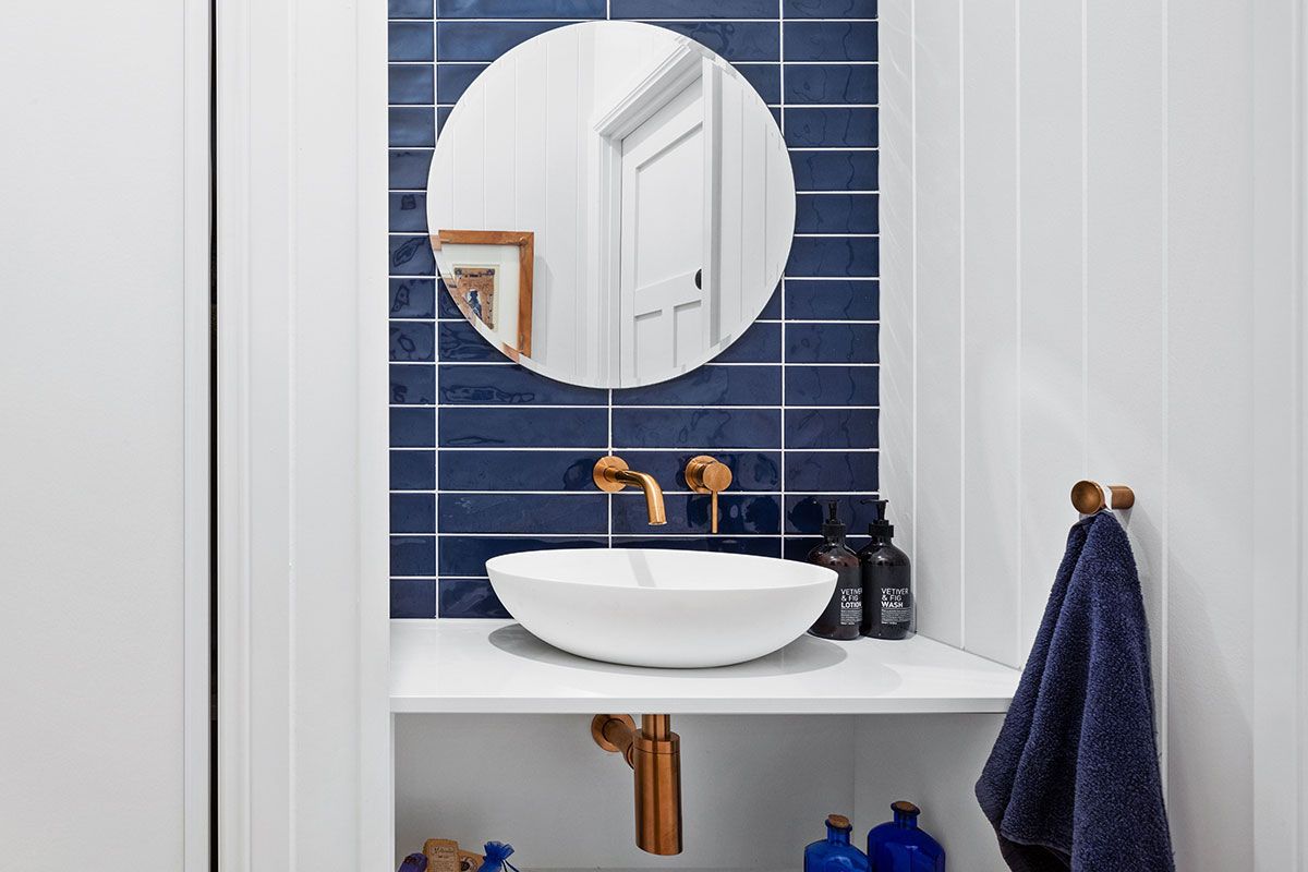 a bathroom with a sink , mirror and blue tiles .