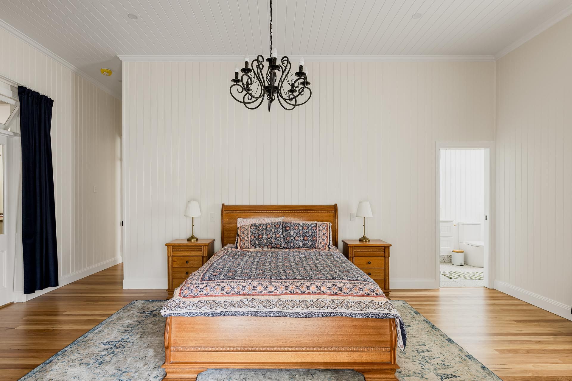 A bedroom with a bed , nightstands , and a chandelier.