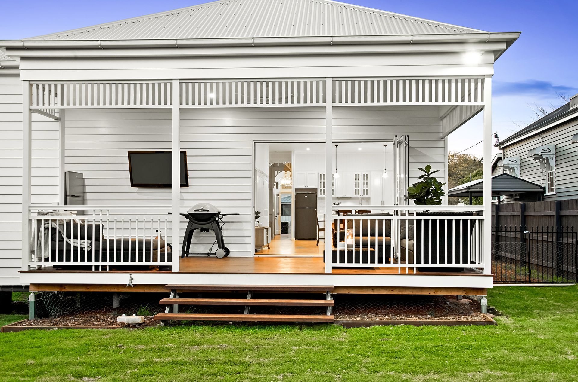 the back of a white house with a porch and stairs