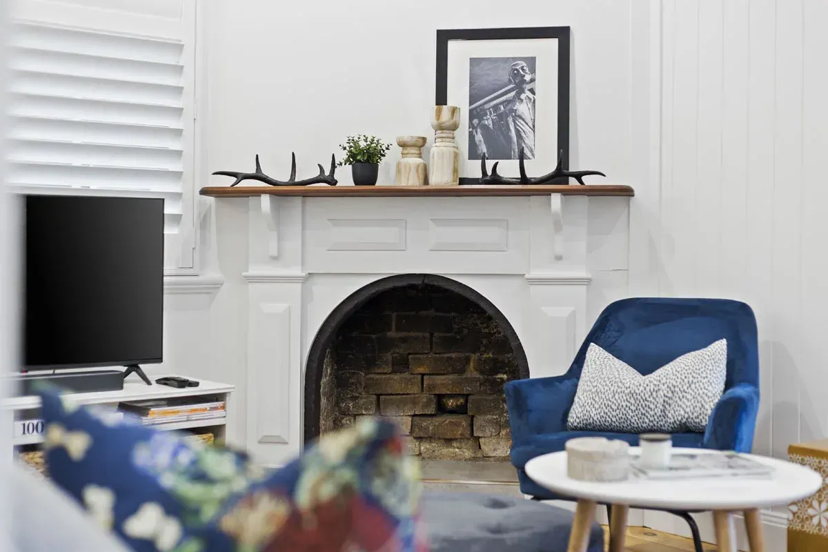 a living room with a fireplace , chair , table and television .