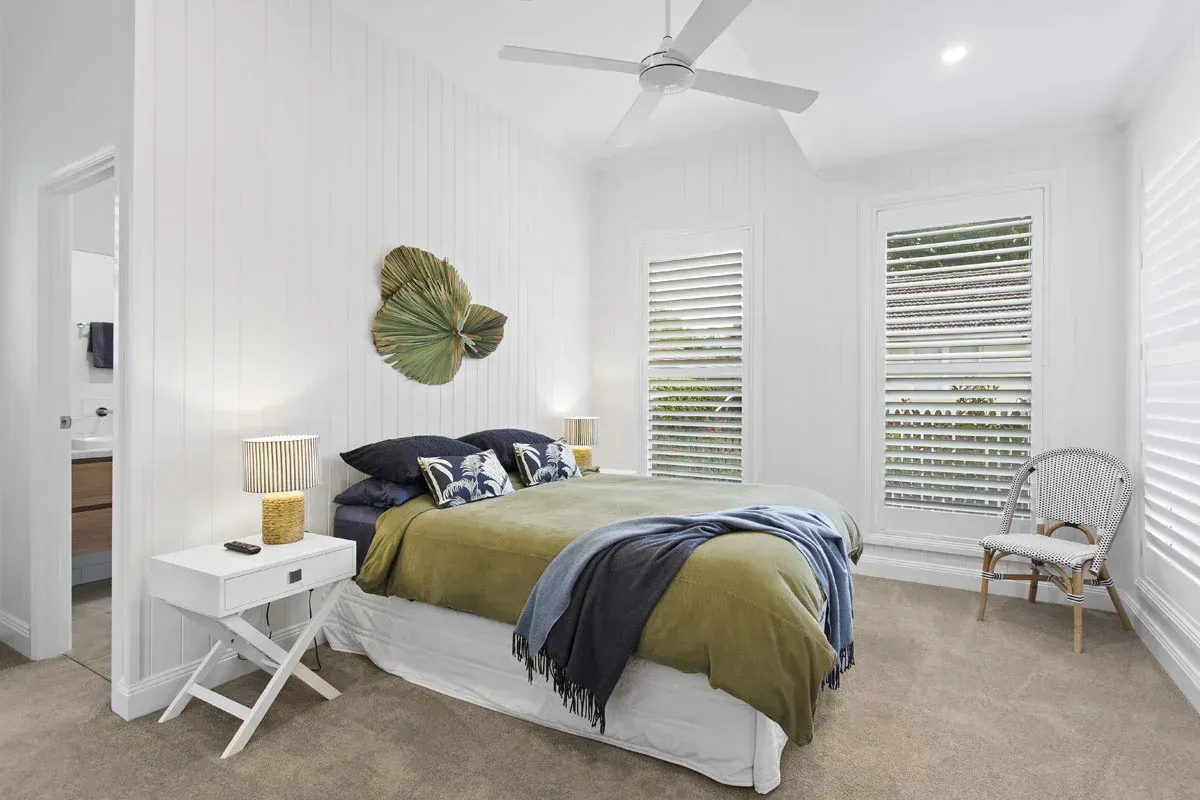 a bedroom with a bed , nightstand , chair and ceiling fan .