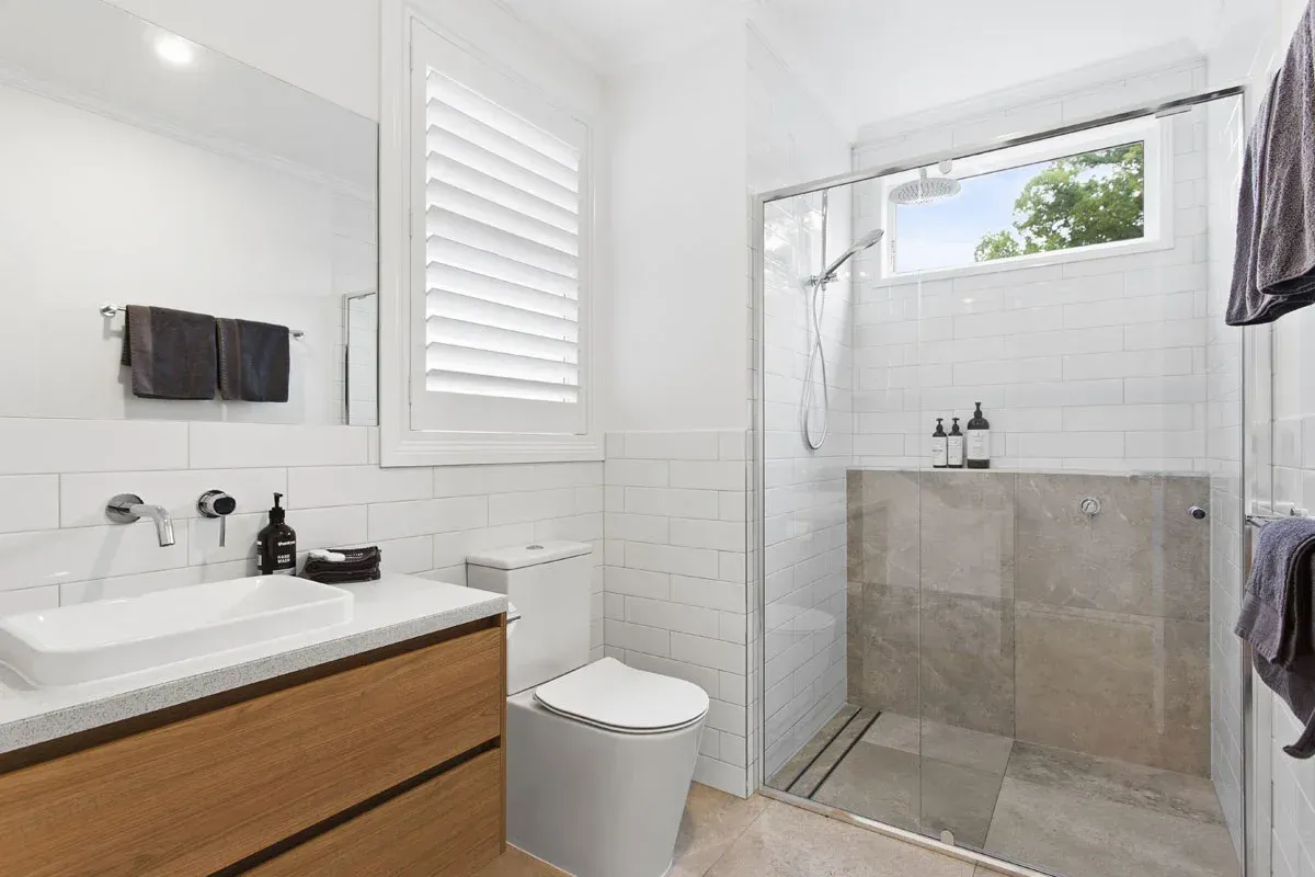 a bathroom with a toilet , sink and walk in shower .