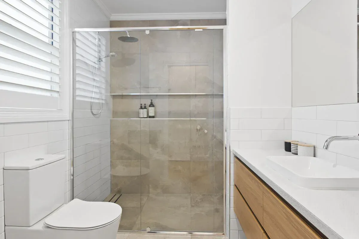 a bathroom with a toilet , sink and walk in shower .