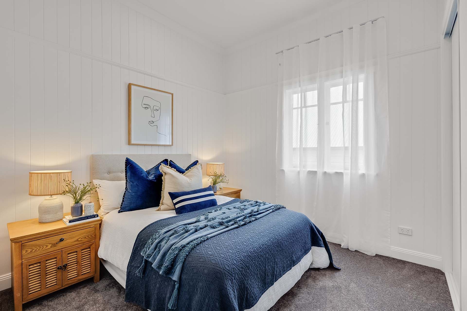 a bedroom with a bed , nightstand , lamp and window .