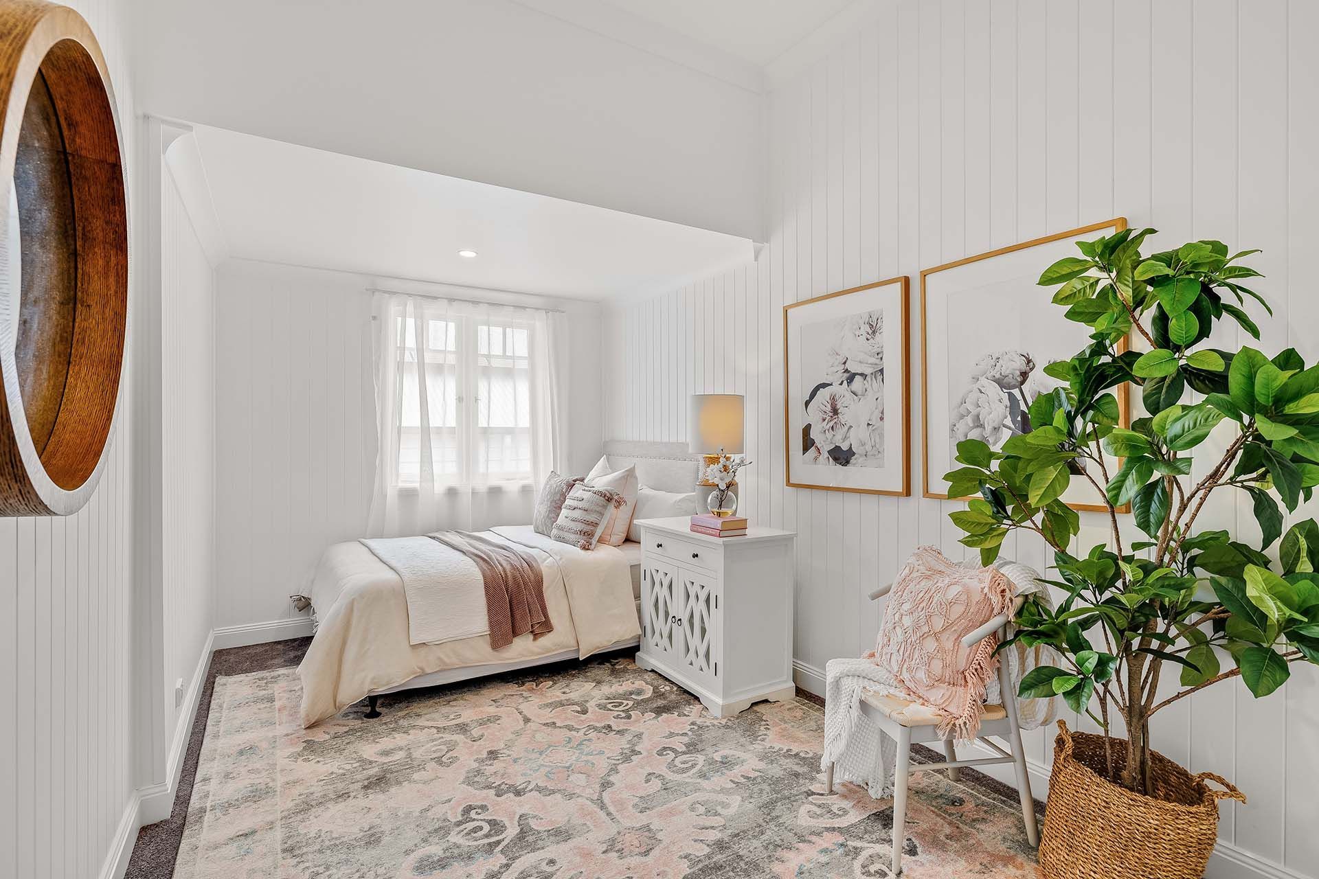 a bedroom with a bed , nightstand , chair and plant .