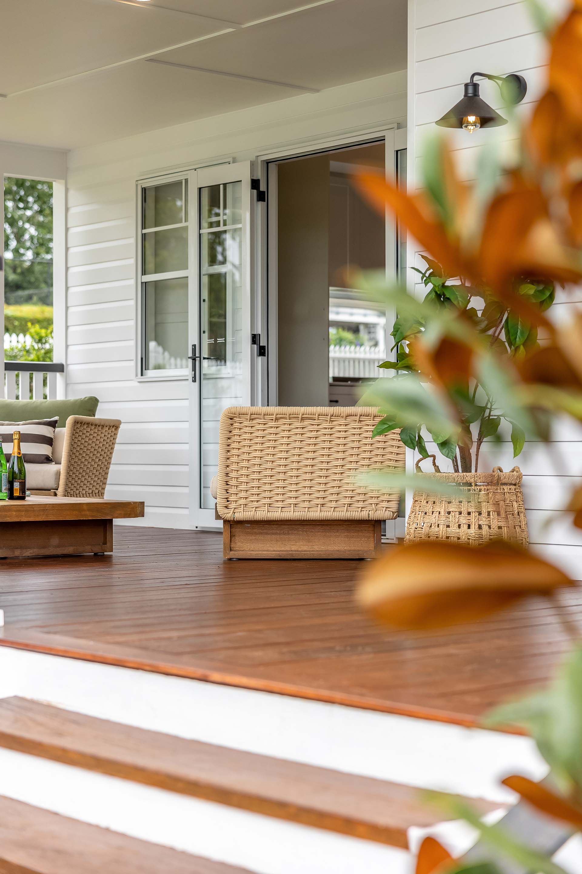 a patio with a wicker chair and a coffee table .