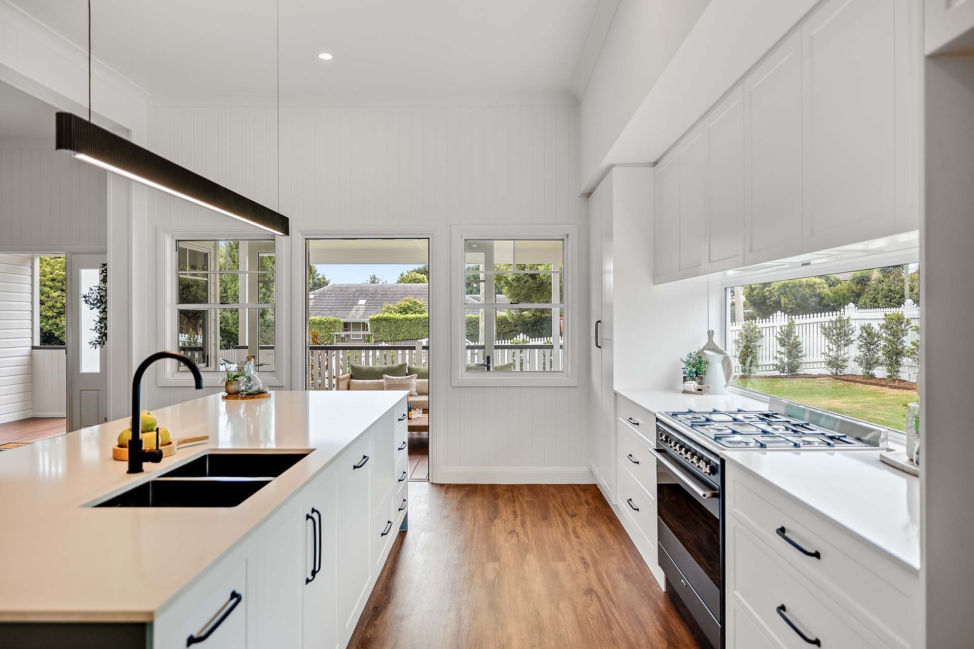 a kitchen with white cabinets , a sink , a stove and a window .